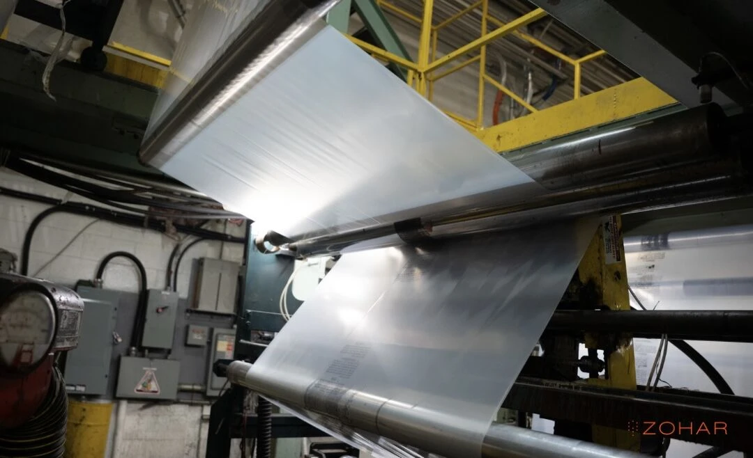 Clear polyethylene film running over the rollers of a Zohar production line